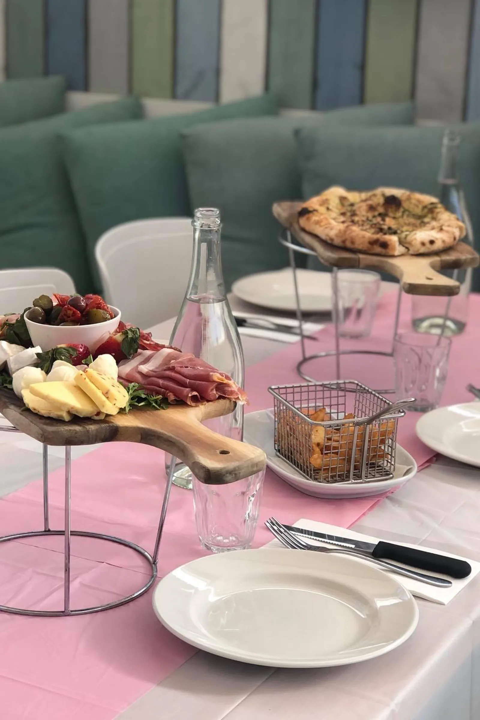 A charcuterie board and wood-fired pizza on the table, cushioned booth seating behind