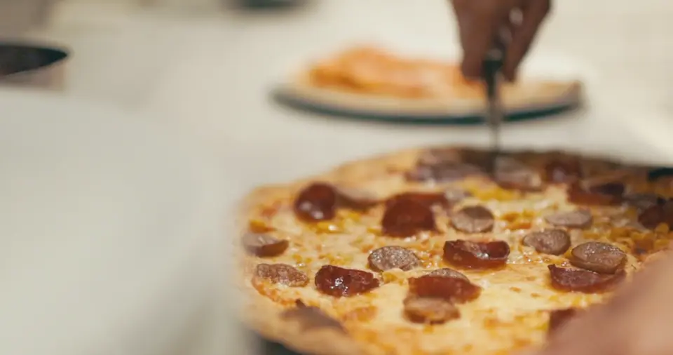 A pizza being cut into slices on the board